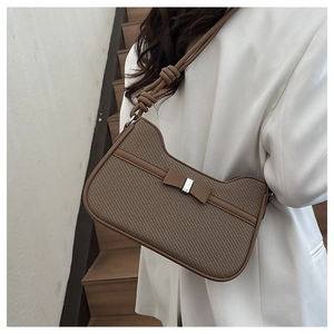 Detail of a brown woven shoulder bag featuring a leather bow and thick rope knot strap