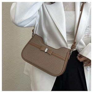 Close-up of brown woven shoulder bag featuring a stylish bow and silver buckle detail