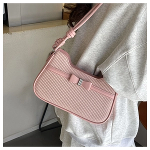 Close-up of pink woven shoulder bag with a stylish bow and knotted strap detail