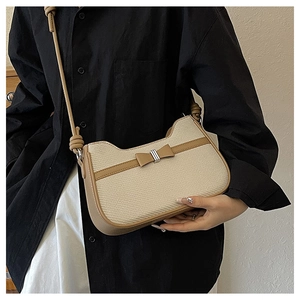 Detail of minimalist cream woven and leather handbag with a delicate bow accent
