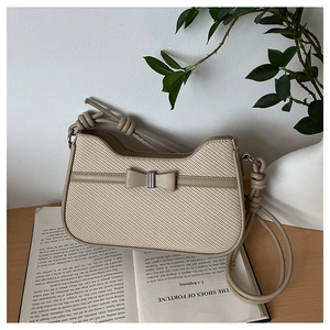 Close-up of woven texture shoulder bag with decorative bow and stylish knot strap detail