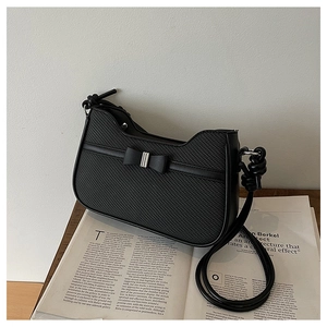 Close-up of black textured shoulder bag featuring a stylish bow and silver metal buckle