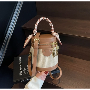 Detail of a brown leather and woven bucket bag featuring a silk scarf wrapped handle