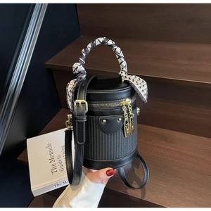 Detail of black textured bucket bag with silk scarf handle on wooden stairs