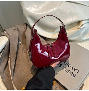 Detail shot of burgundy patent leather crescent bag with silver metallic hardware buckle