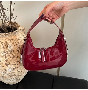 Detail of burgundy patent leather crescent hobo bag with sleek silver dual zippers