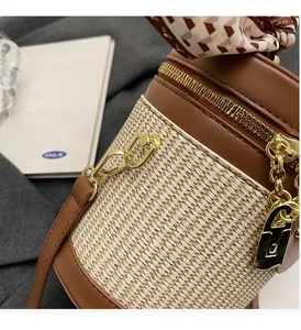 Detail of woven straw bucket bag with brown leather trim and vintage scarf handle
