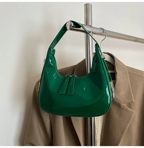 Detail of green patent leather crescent bag featuring glossy finish and dual zipper pulls
