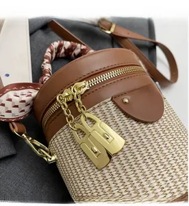 Detail of bicolored bucket bag with gold zippers and decorative handle scarf