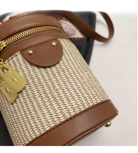 Detailed macro view of straw woven texture and brown leather stitching on a bucket bag