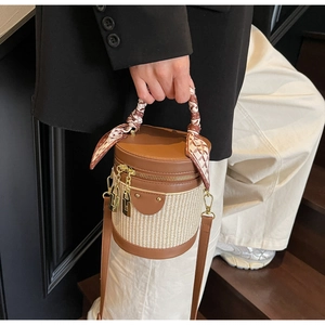 Detail of a brown leather and woven bucket bag with silk scarf handle and gold hardware