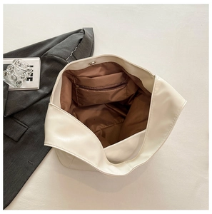 Internal view of large white bucket bag showing brown lining and functional zip pocket