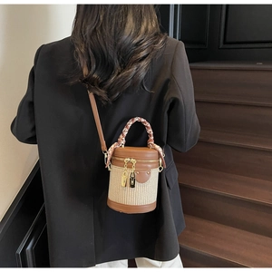 Detail of a chic bucket bag with woven base and silk scarf wrapped handle on model