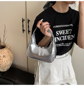 Silver crescent underarm bag with metallic leather texture and double zipper detail