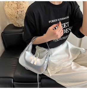 Silver crescent moon shoulder bag shown on model with dual zipper detail and sleek finish