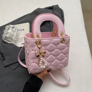 Sac à main rose matelassé en cuir avec clous dorés et pendentif perle élégant
