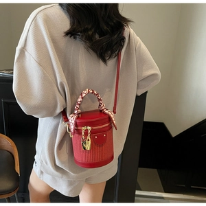Detail of red woven bucket bag with silk scarf handle and golden double zippers