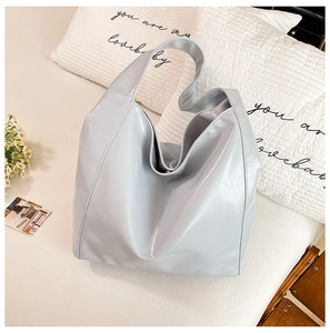 Detail of light gray soft leather bucket bag with wide strap on home lifestyle background