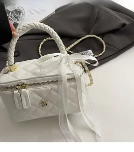 Detailed view of white quilted crossbody bag with lace bow and camellia metal buckle