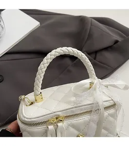 Macro shot of white quilted leather bag with woven handle and lace bow detail