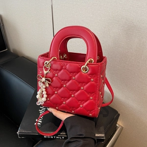 Sac à main rouge matelassé avec clous étoiles et charme perle sur un support