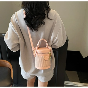 Detailed view of a pink bucket bag with a silk scarf handle worn as a crossbody bag