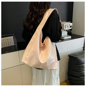 Detail of soft glossy light pink hobo bag with a wide shoulder strap worn by a model