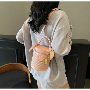 Detail of pink woven bucket bag with heart silk scarf handle and gold lock charm detail