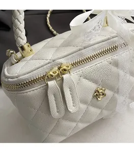 Detail of white quilted handbag with golden camellia hardware and smooth zipper