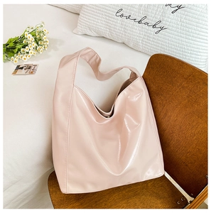 Detail of pink PU leather hobo bag with glossy finish on a dark wooden chair