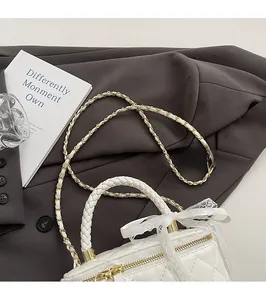 Close-up of quilted white crossbody bag with woven handle and gold chain strap detail