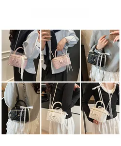 Quilted crossbody bag with lace bow and gold floral pendant in pink, black, and white