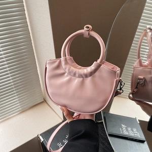 Pink crescent saddle bag with round handle and detachable strap in soft synthetic leather
