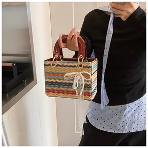 Détail d'un sac à main tressé coloré avec poignées en cuir rouge et breloque en perles