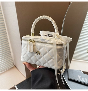 Detail of white quilted crossbody bag featuring a woven handle and lace ribbon decoration