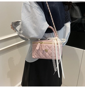 Detail of pink quilted box bag with lace bow and woven handle on person