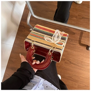 Détail du sac tissé multicolore avec poignées en cuir rouge et pendentif en perles