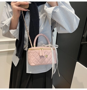 Close-up of pink quilted leather bag with golden flower detail and lace ribbon handle