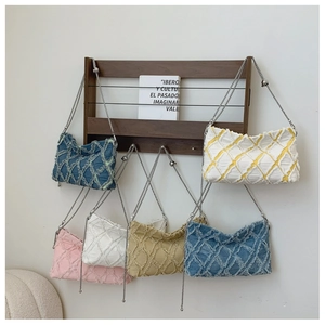 Close-up of quilted denim shoulder bags with frayed edges and chain straps in multiple colors