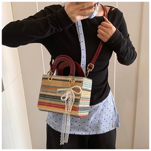 Détail du sac tissé à rayures avec anses rouges vernies et nœud en dentelle blanche