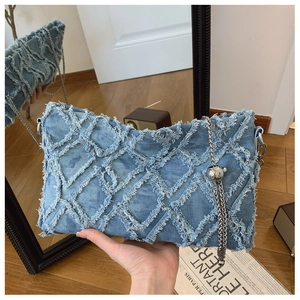 Detail of light blue denim shoulder bag featuring frayed diamond lattice and silver chain