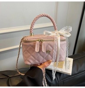 Detailed view of pink quilted handbag with woven handles and white lace bow decoration