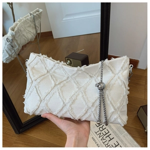 Detail of white denim underarm bag featuring quilted frayed edges and silver chain pendant
