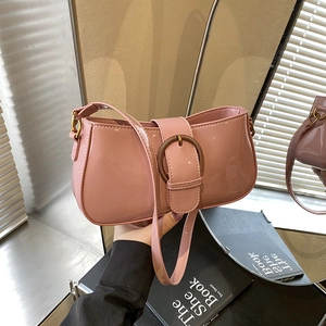 Sac baguette en cuir verni rose avec boucle métallique dans un décor d'intérieur