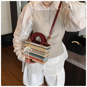 Détail du sac à main tissé coloré avec poignées en cuir verni rouge et breloque en perles