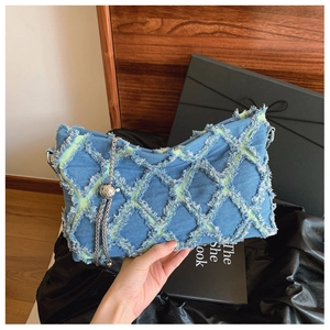 Detail of blue denim underarm bag featuring distressed quilted texture and silver chain