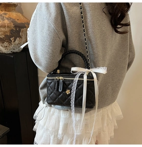 Detailed back view of a black quilted crossbody bag with gold chain and lace bow