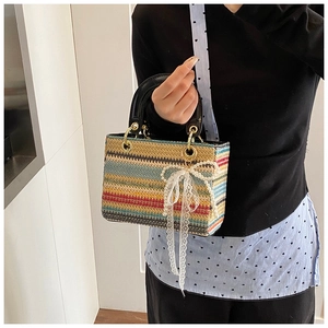 Détail d'un sac à main tressé coloré avec nœud en dentelle et bandoulière à cœurs