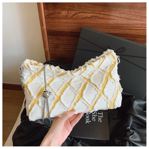 Detail of yellow denim bag with white diamond fraying and silver chain strap details