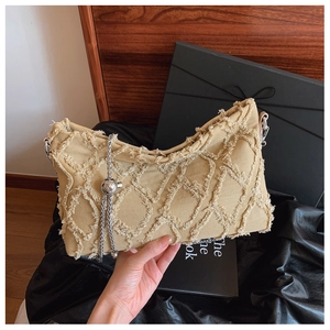 Detail of khaki denim underarm bag featuring frayed edge quilting and silver chain strap